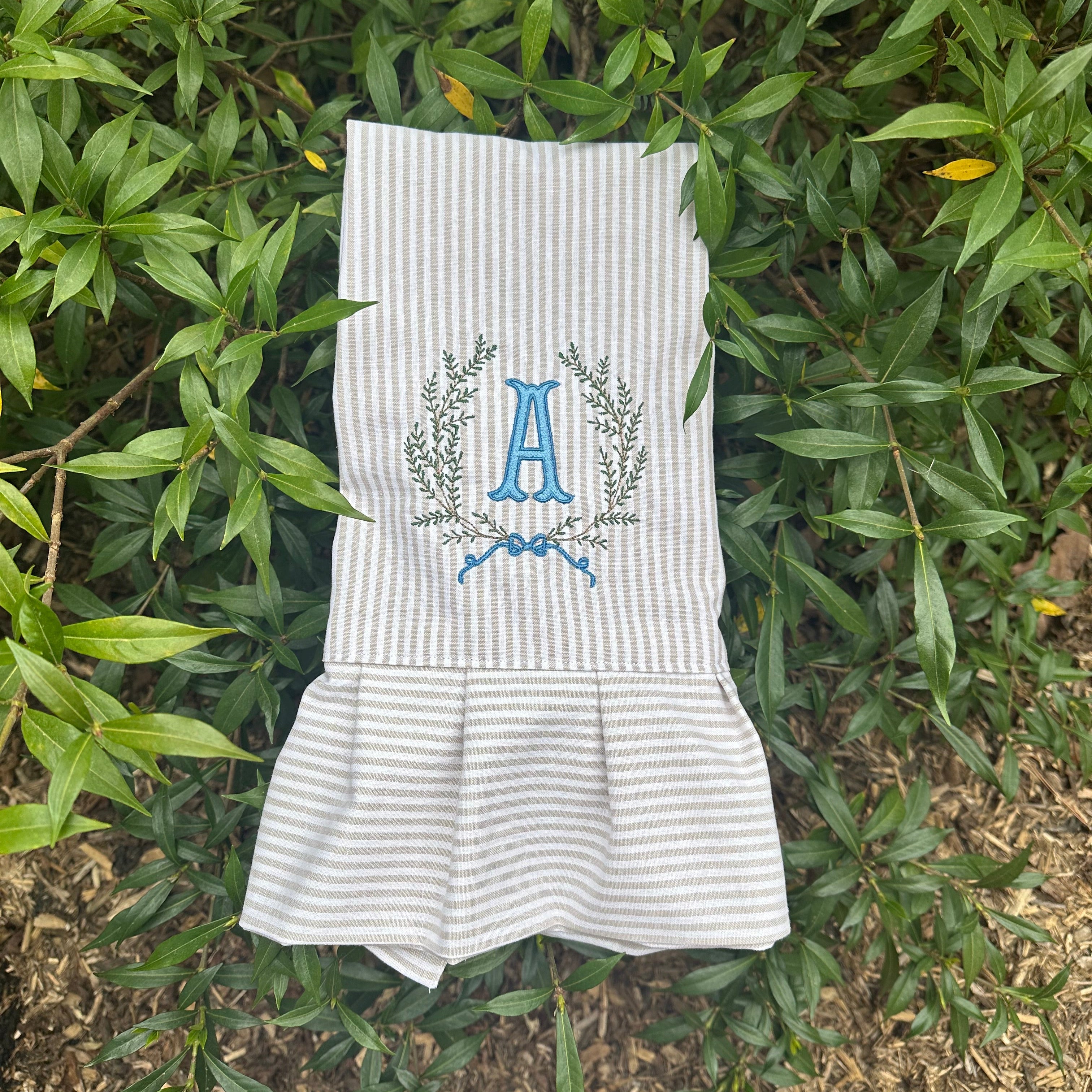 Tea towel with blue embroidery on a green leafy background