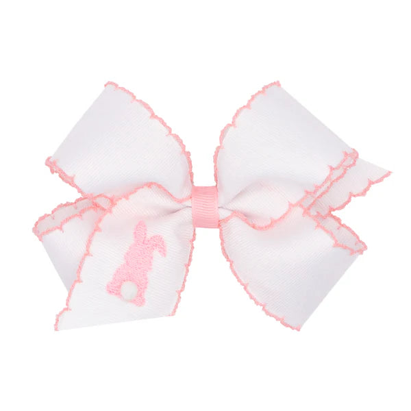 White bow with pink edges and a pink bunny on a white background