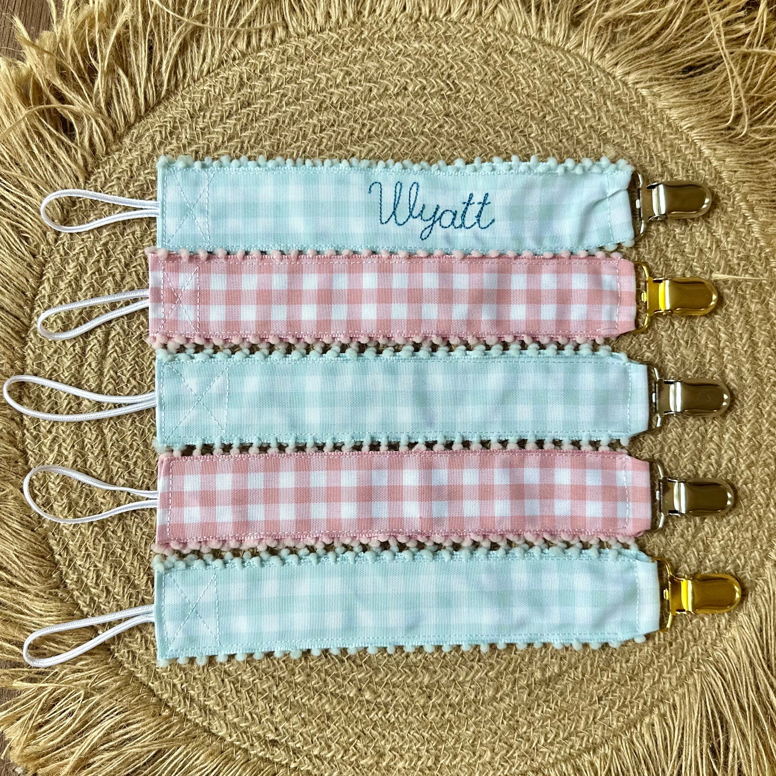 Set of three fabric keychains with checkered patterns on a woven mat.