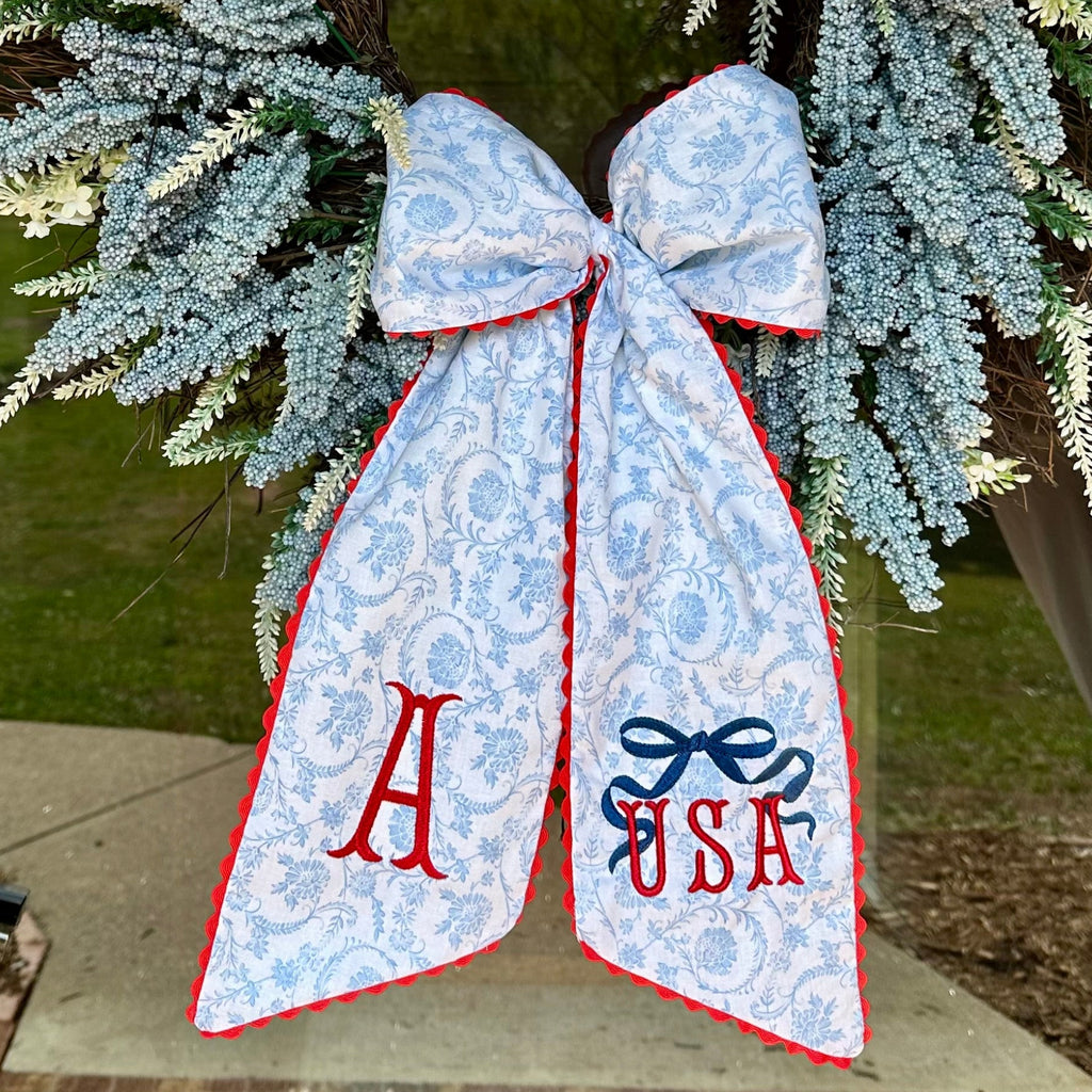 Decorative wreath with a blue bow featuring the letters 'A' and 'USA' on a door.
