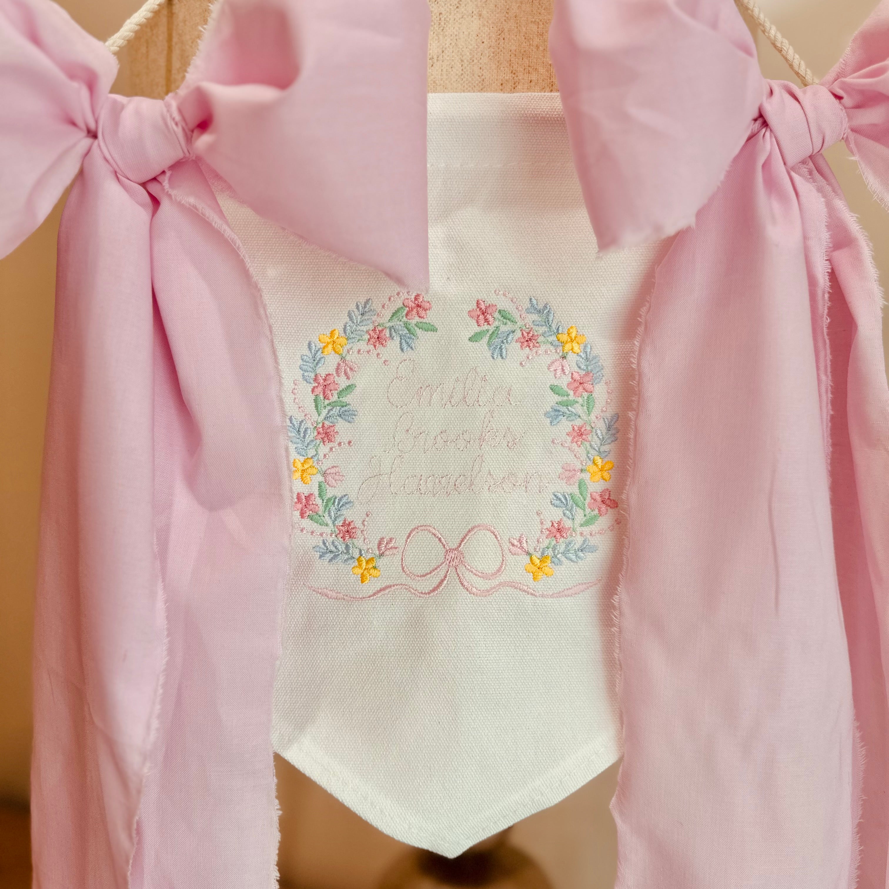 White baby banner with floral crest and baby’s name. Had pink ribbons. 