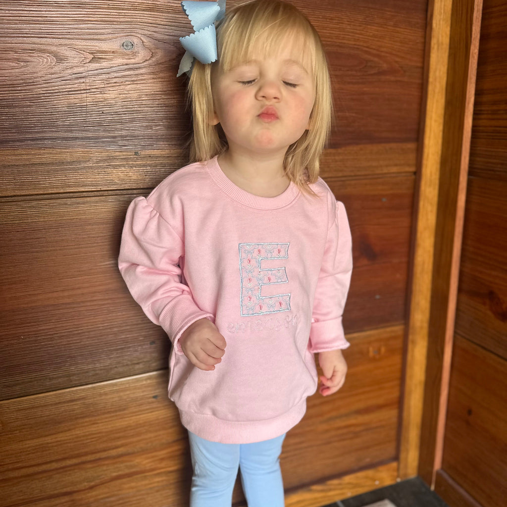 Girl in pink sweatshirt with floral embroidered on shirt