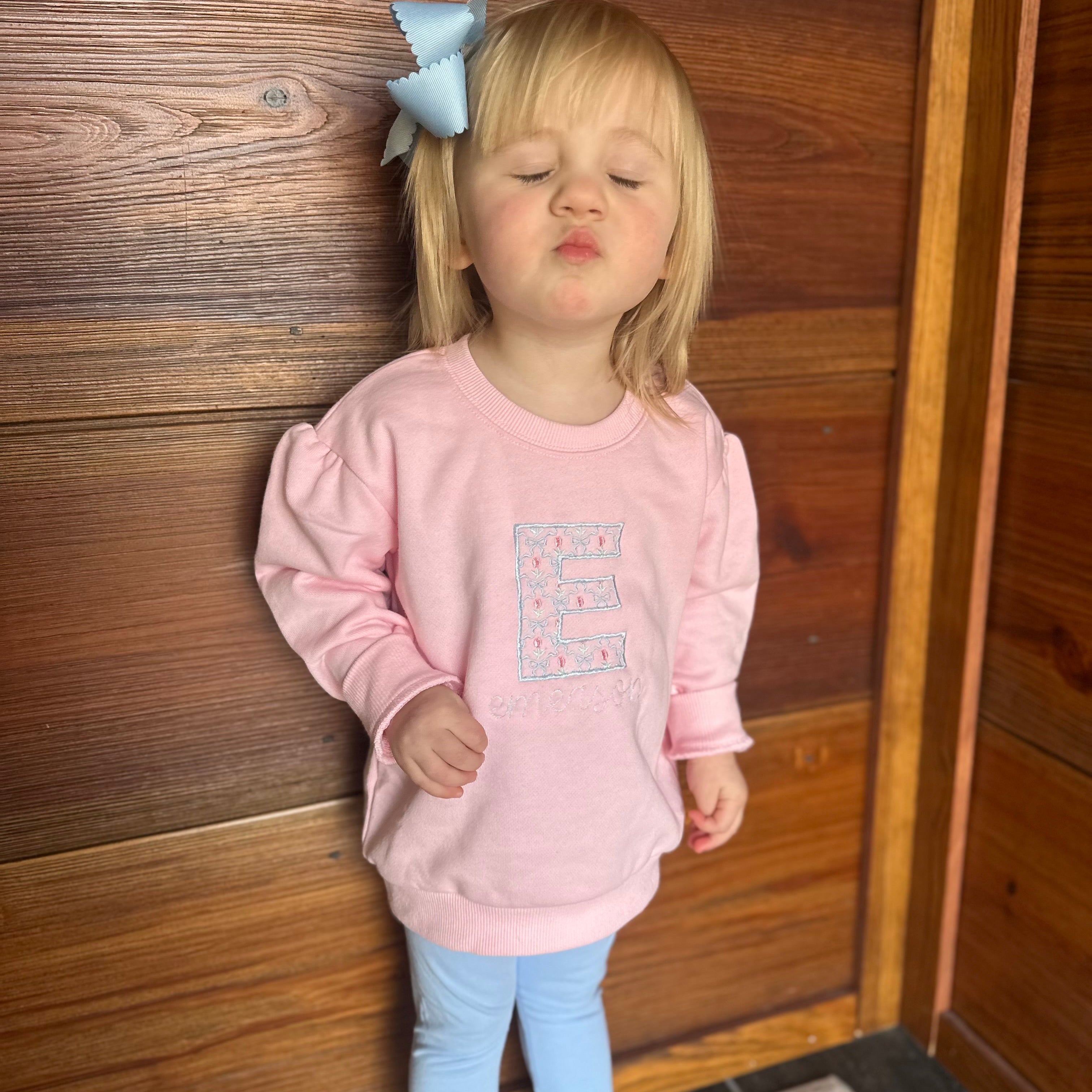 Girl in pink sweatshirt with floral embroidered on shirt